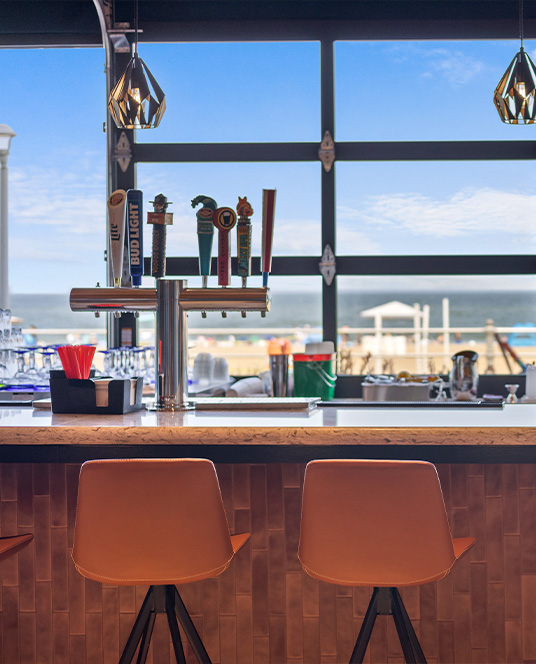 Sunset view from RANGSA’s seaside patio with a table set for waterfront dining